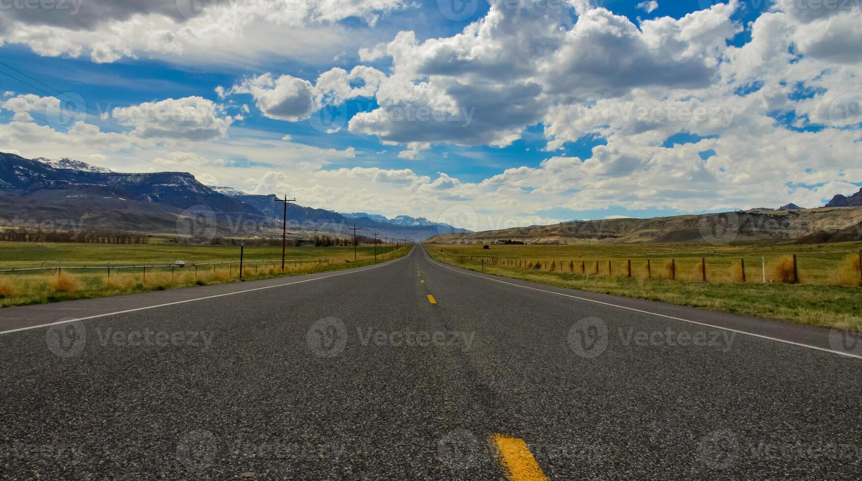 The landscape is in the wild. A road going into the distance, white clouds on the horizon. photo