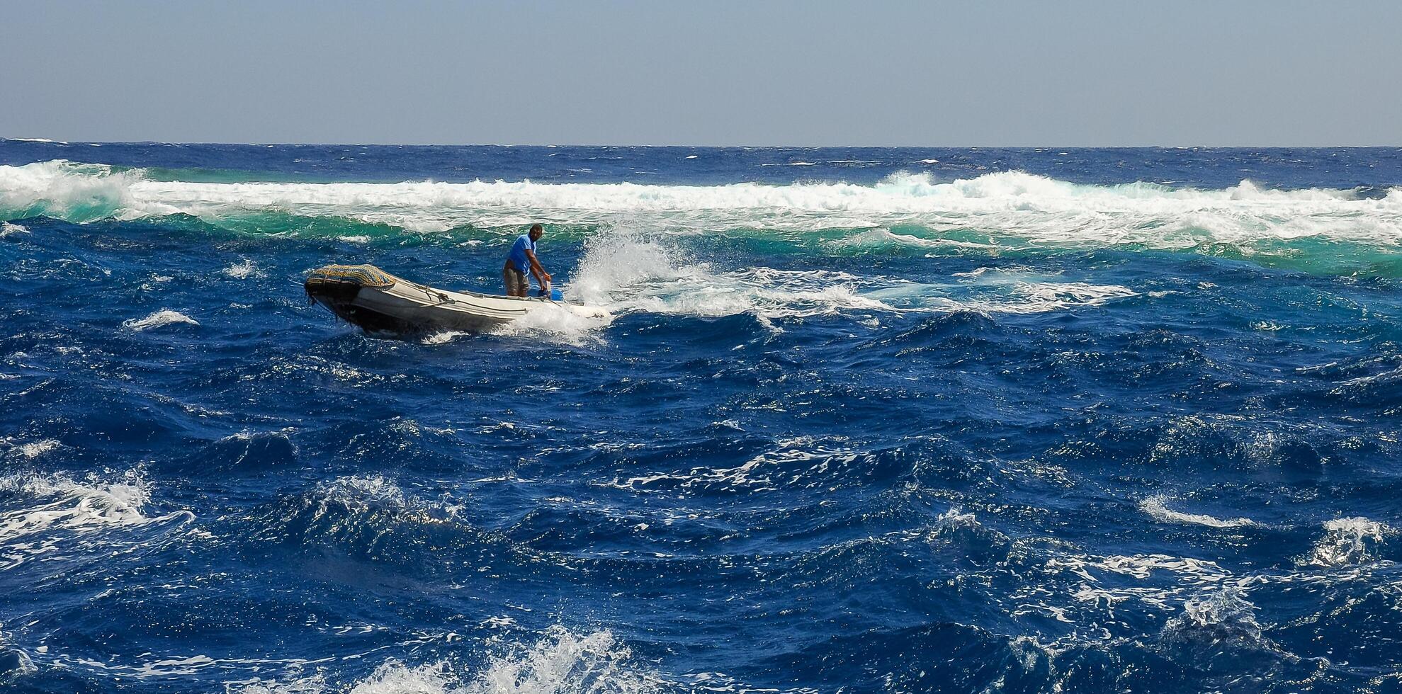 Rubber boat with sailor on mooring rope to Big Brother island of diving yacht during a storm, Red Sea photo