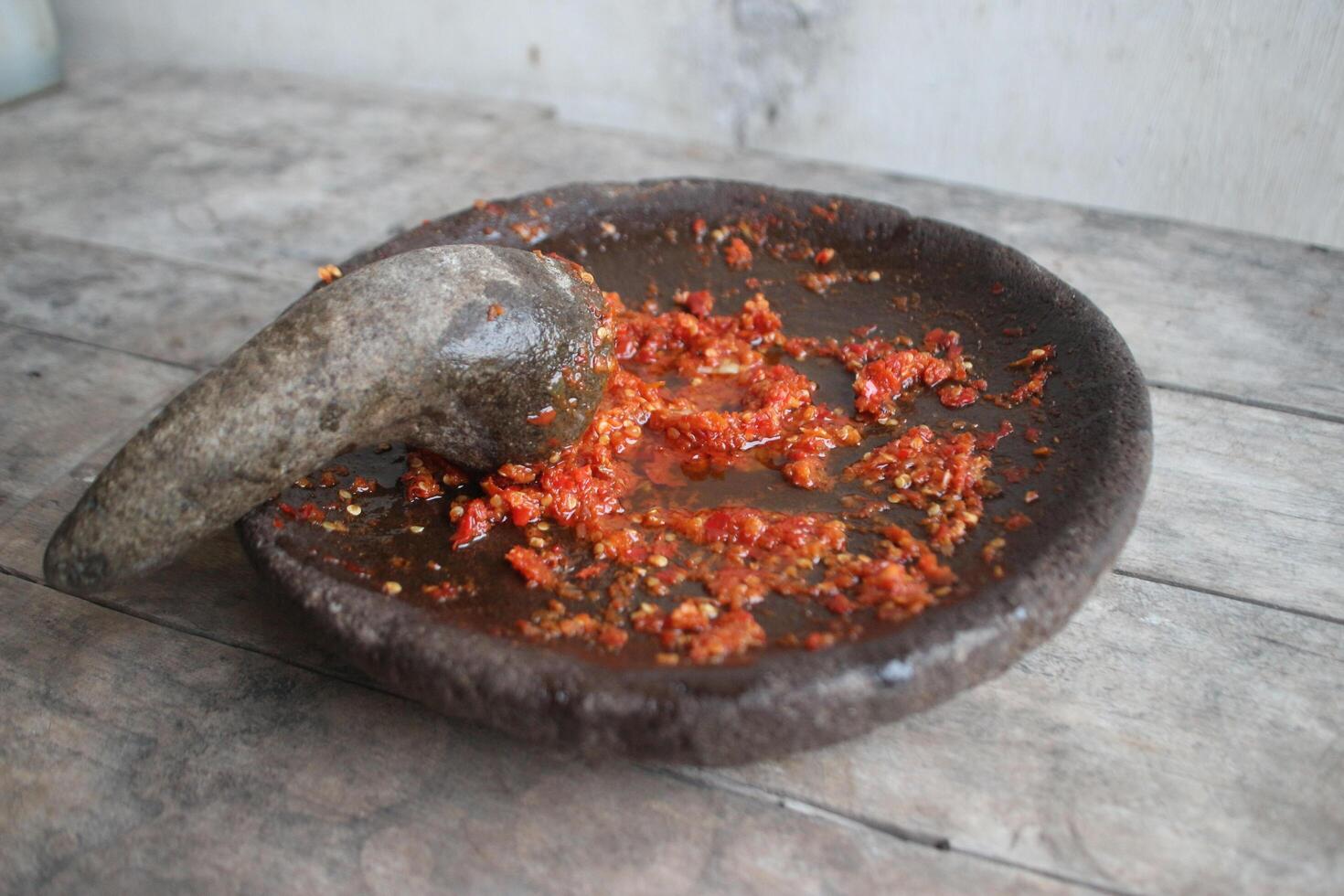Sambal cobek or traditional Indonesian chili sauce, made from chilies, spices and other kitchen spices. made using a stone mortar and pestle. suitable for menu books. photo