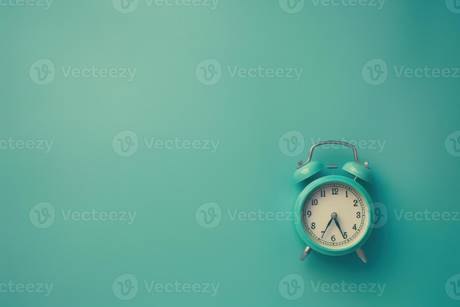 A vintage alarm clock rests against a soft turquoise background, its hands pointing to early morning light photo