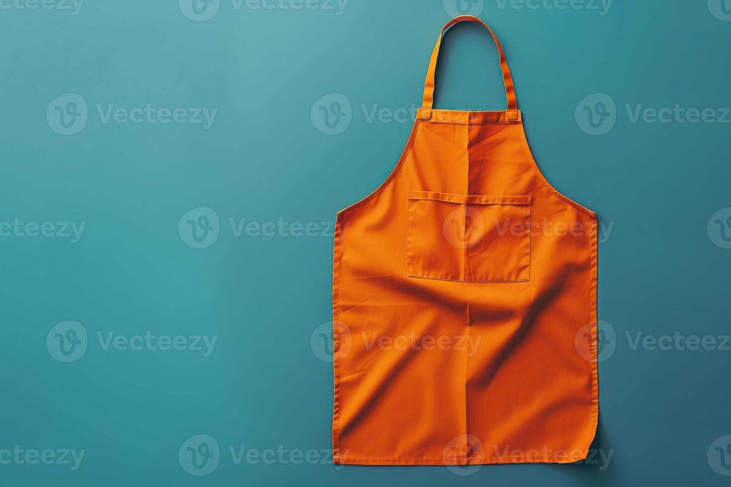 Bright orange apron hanging against a teal backdrop in a kitchen setting, ready for culinary adventures photo
