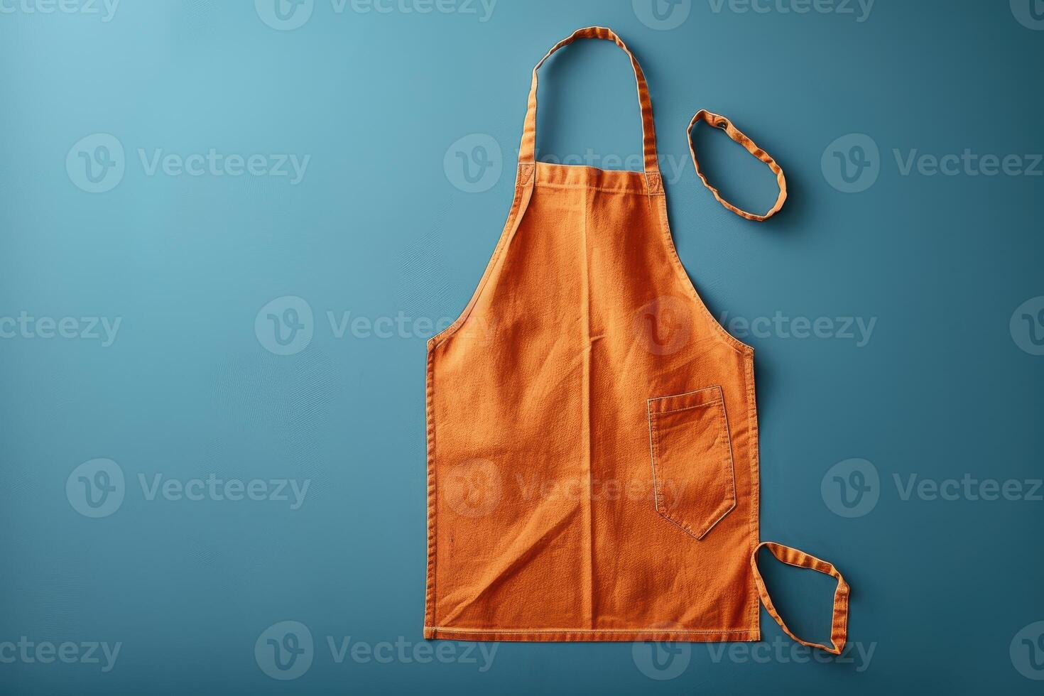 An orange apron laid flat against a vibrant blue background captures the essence of culinary creativity in a kitchen setting photo