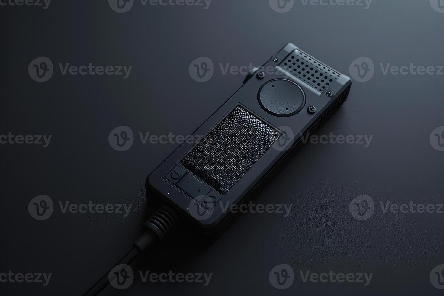 A sleek black audio recorder rests on a dark surface, capturing sounds in a minimalist workspace illuminated by soft light photo
