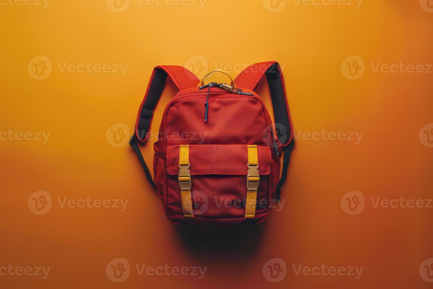 A vibrant red backpack stands out against a bright yellow background, showcasing its unique design and playful straps in a minimalist setup photo