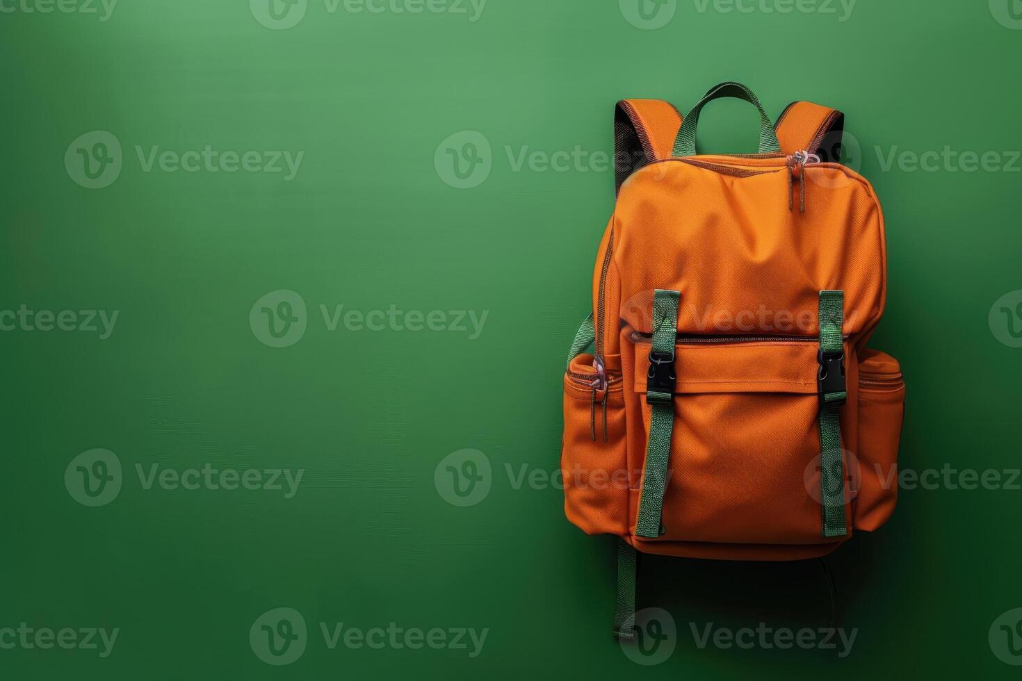 An orange backpack stands against a vibrant green background, showcasing its stylish design and functional features photo