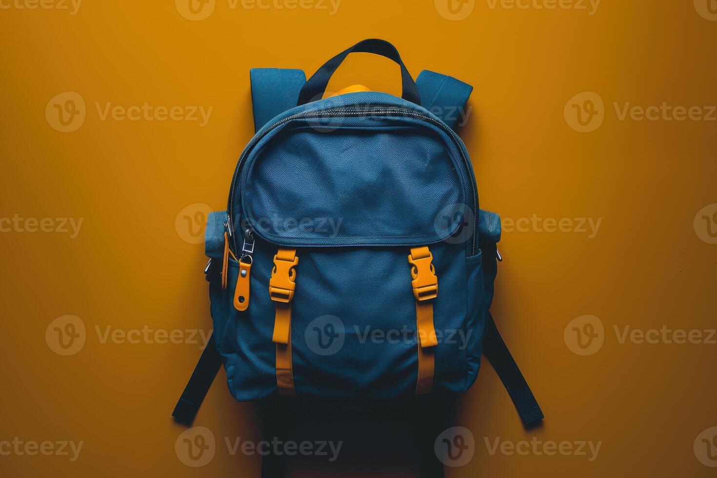 A vibrant blue backpack with yellow straps rests against a bright orange background, capturing a sense of adventure and exploration photo