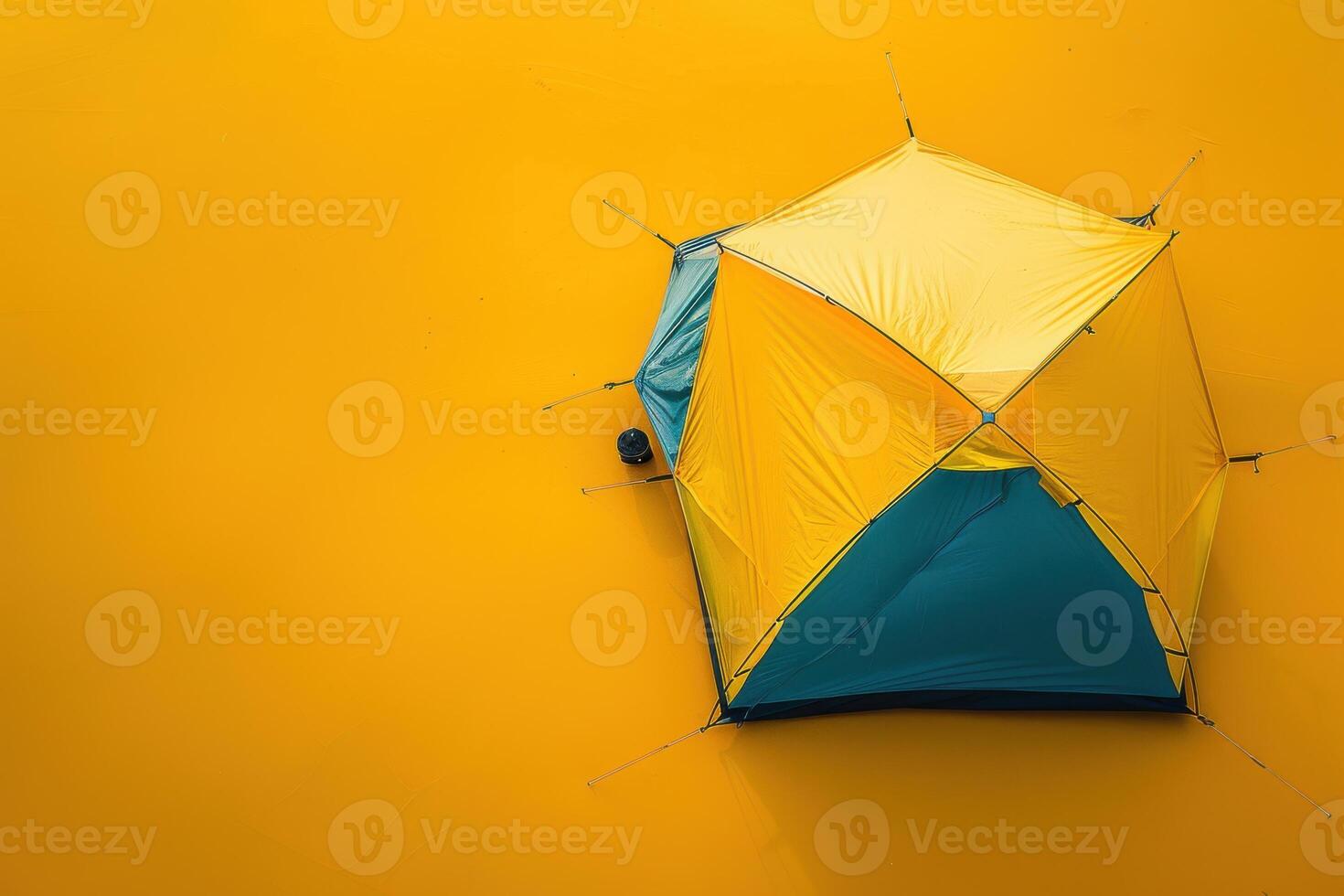 A vibrant yellow and blue camping tent set against a bright yellow backdrop in the golden light of late afternoon photo