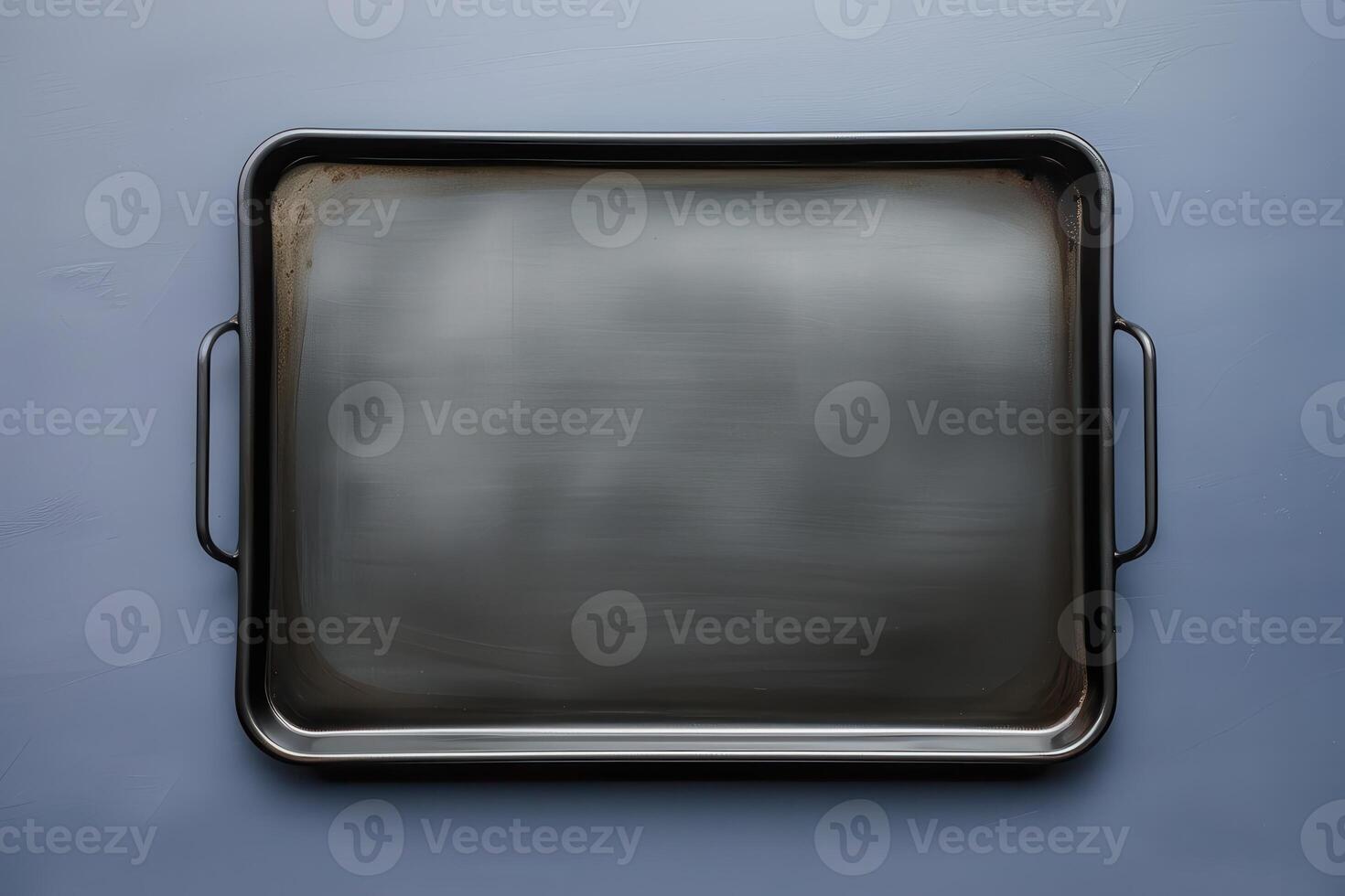 Shiny baking tray resting on a dark surface illuminated by soft light photo