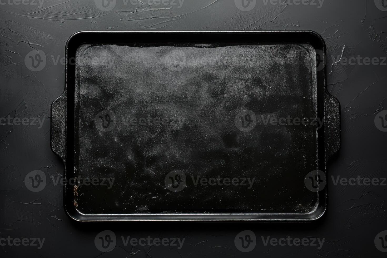 A polished baking tray resting on a textured dark surface, ready for culinary creations in a cozy kitchen environment photo