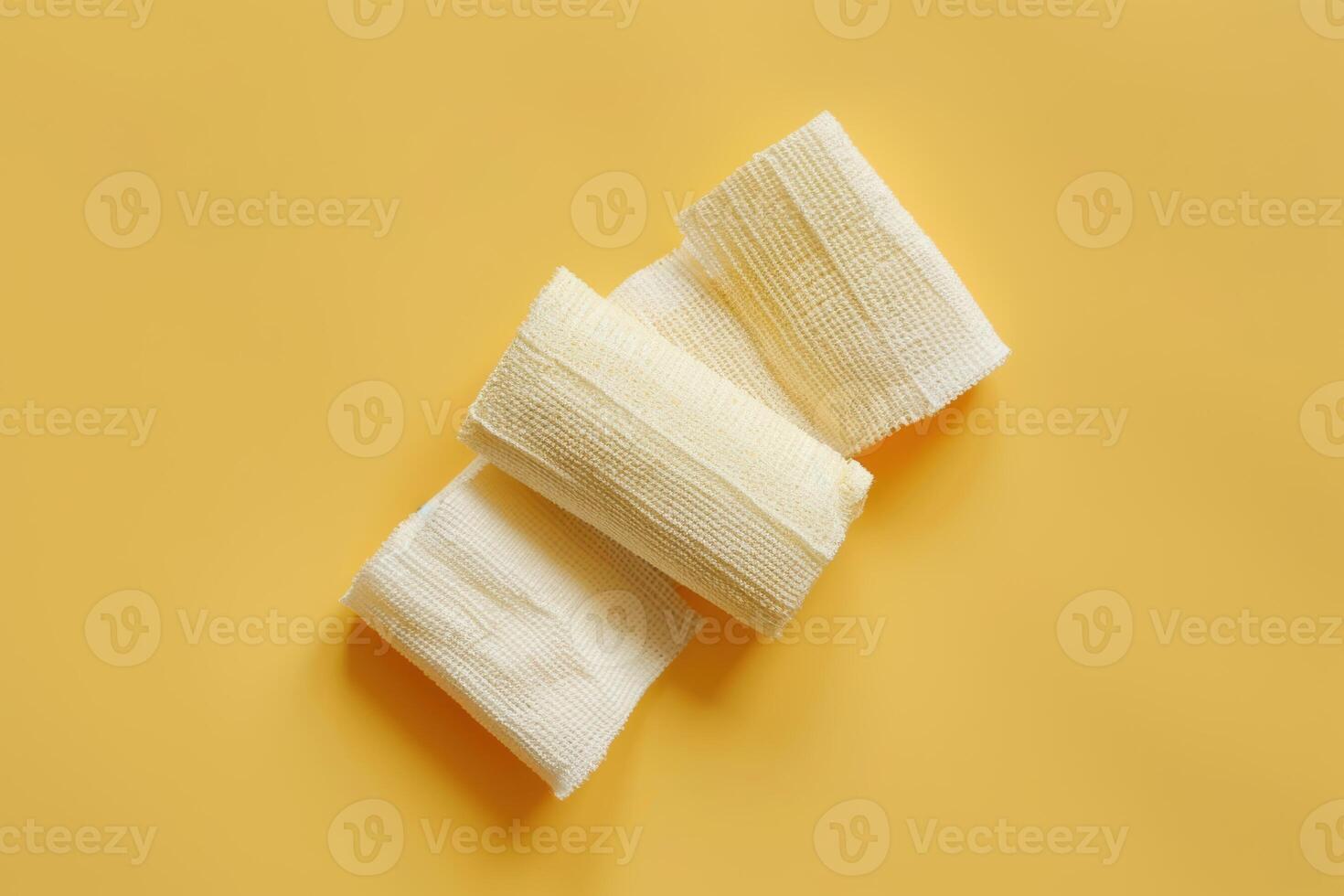 Soft cotton bandages on a vibrant yellow surface creating a soothing contrast in a minimalistic and artistic display photo