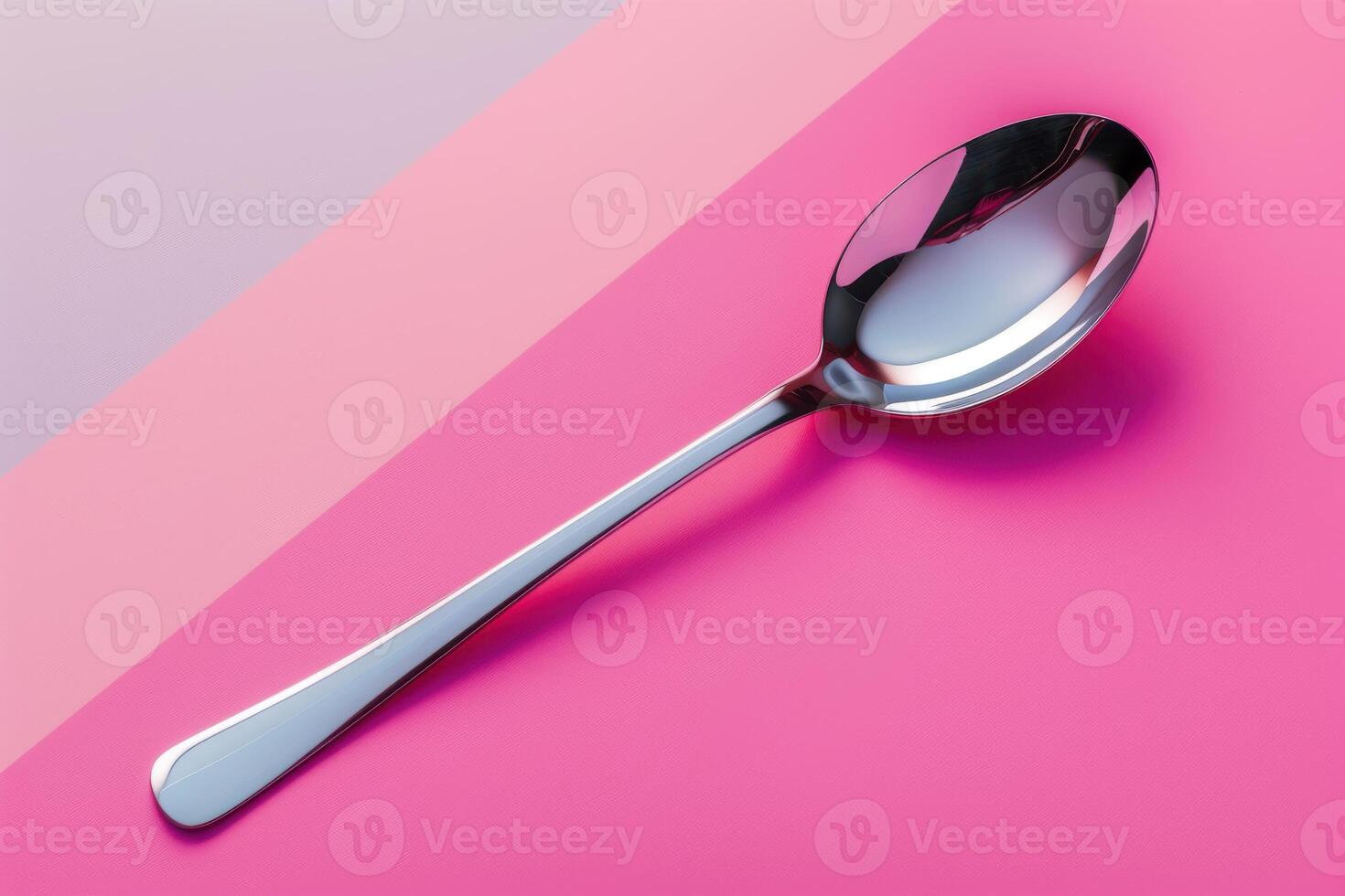A sleek stainless steel spoon resting on a vibrant pink surface, showcasing its polished design under soft lighting photo