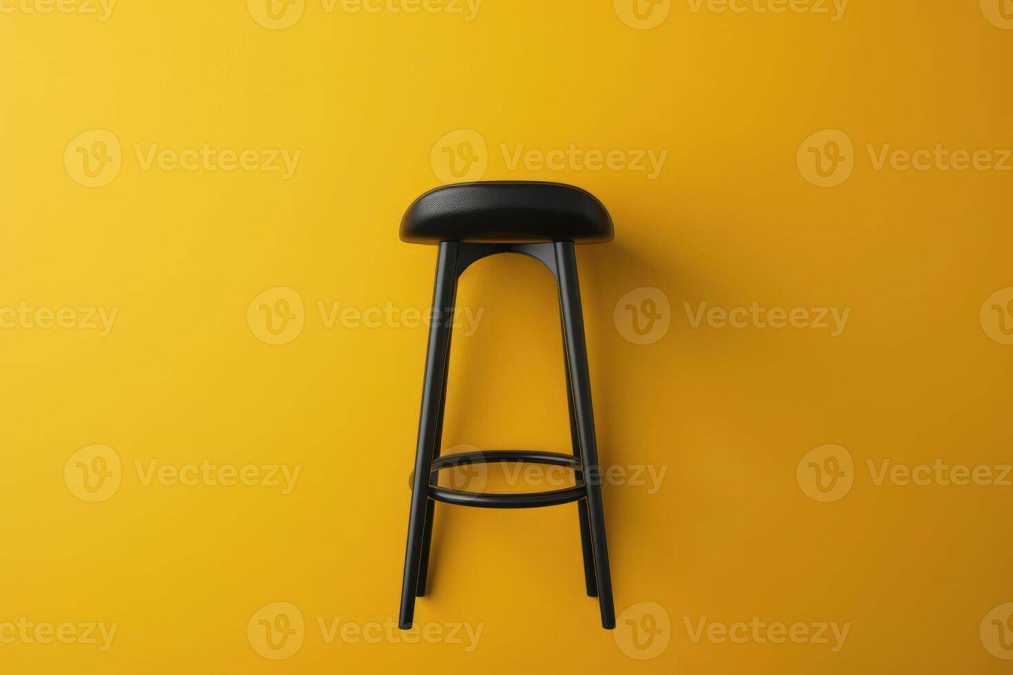 A sleek black stool stands against a vibrant yellow wall, showcasing modern design simplicity in a bright, inviting space photo