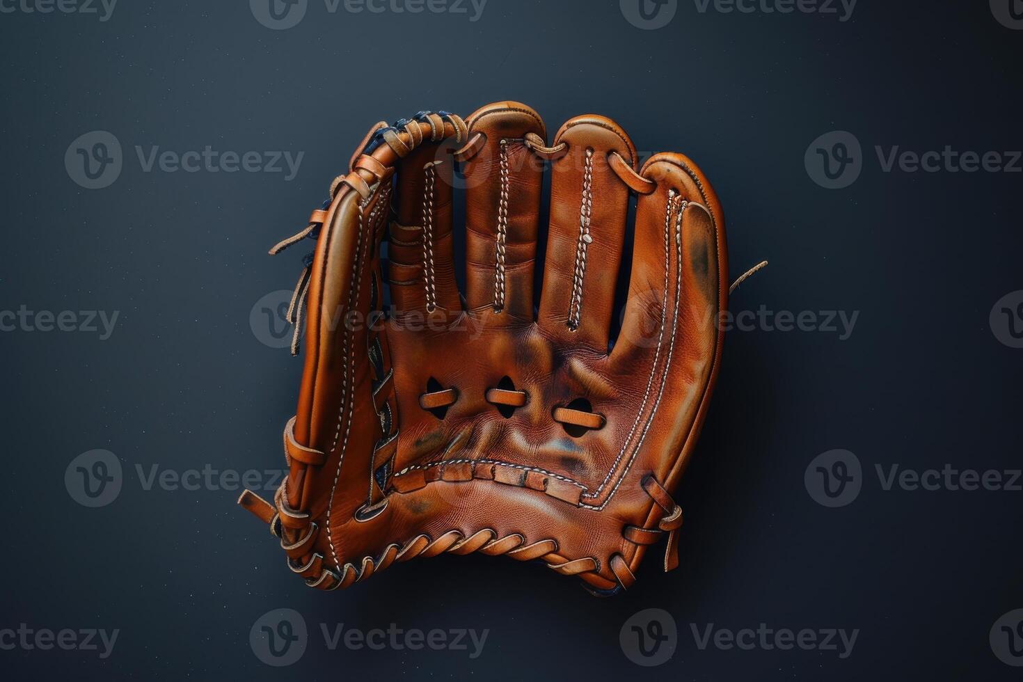 Classic brown leather baseball glove resting on a dark surface, evoking nostalgia for the game on a warm summer afternoon photo