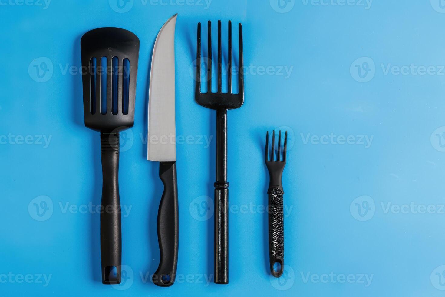 A collection of essential kitchen tools arranged creatively on a vibrant blue backdrop photo