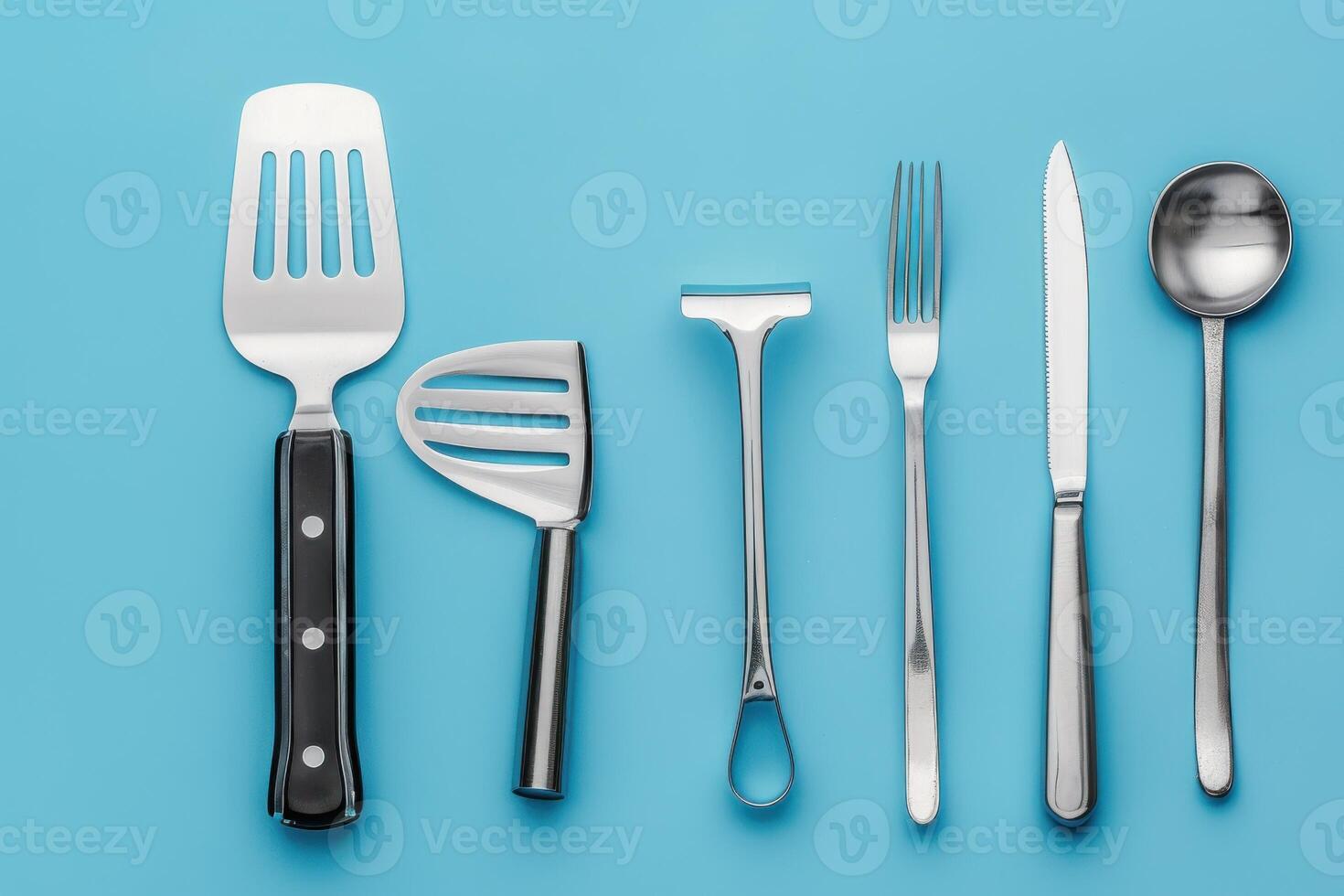 A vibrant collection of kitchen utensils arranged neatly on a bright blue surface, showcasing various tools for cooking and serving meals photo