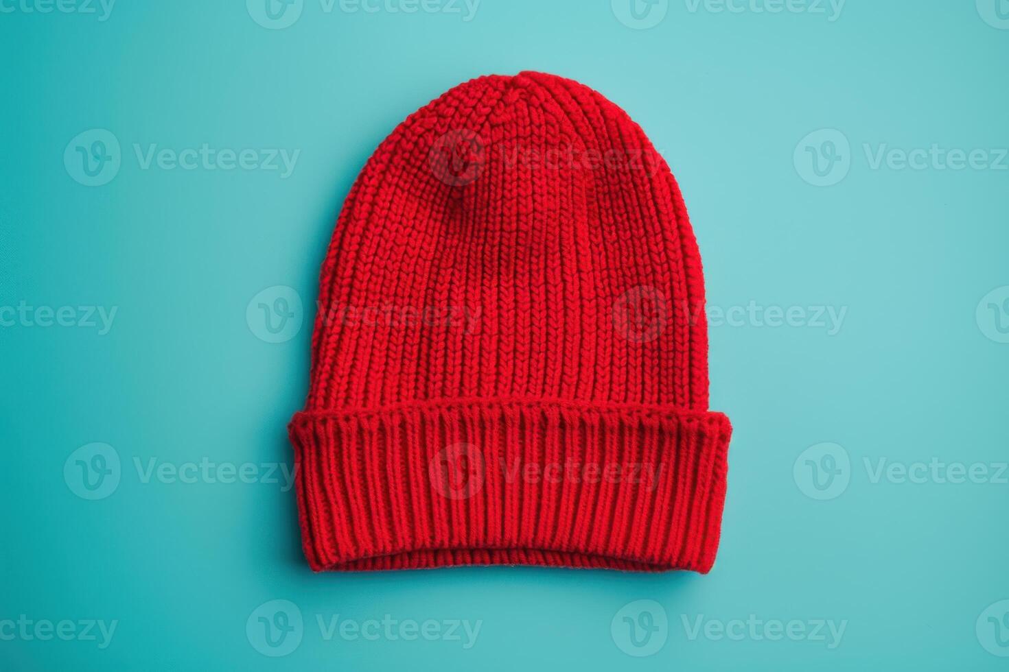A vibrant red beanie lying on a turquoise background, showcasing its cozy texture and warmth photo