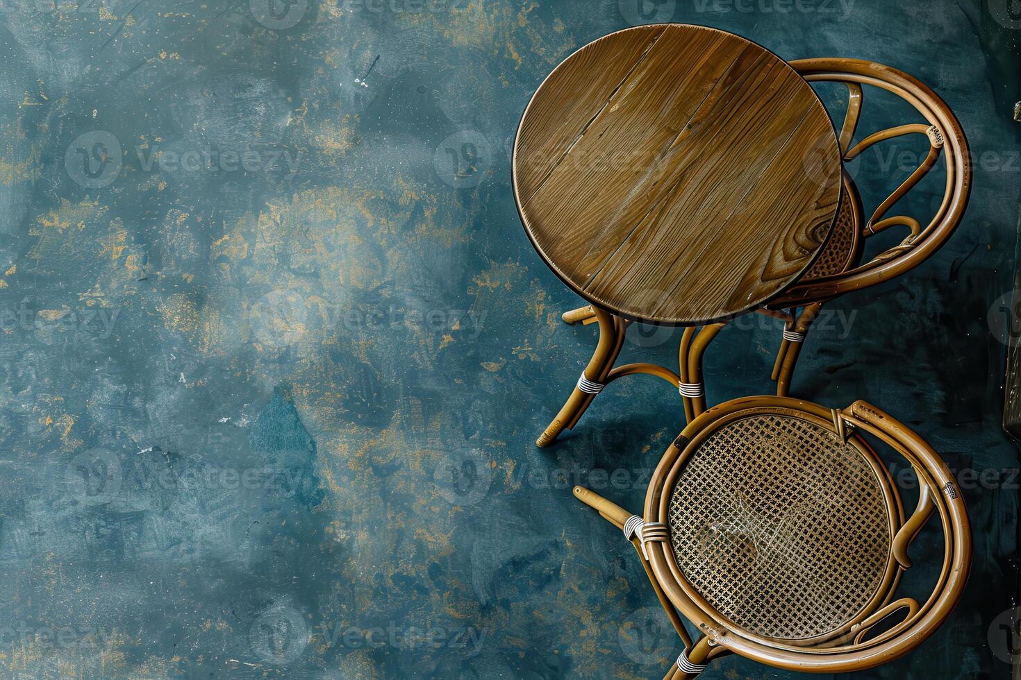 Cozy cafe corner in the afternoon with a rattan table and chair on a textured blue floor photo