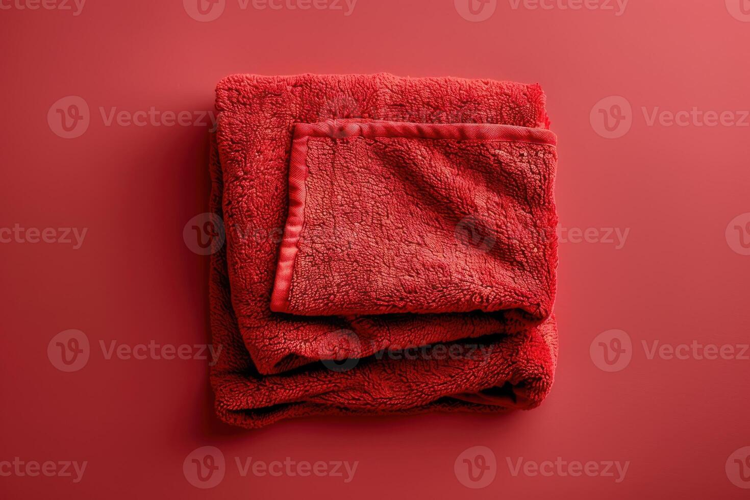 Cozy red towel folded neatly on a vibrant background showcasing warmth and comfort in a minimalist setting photo