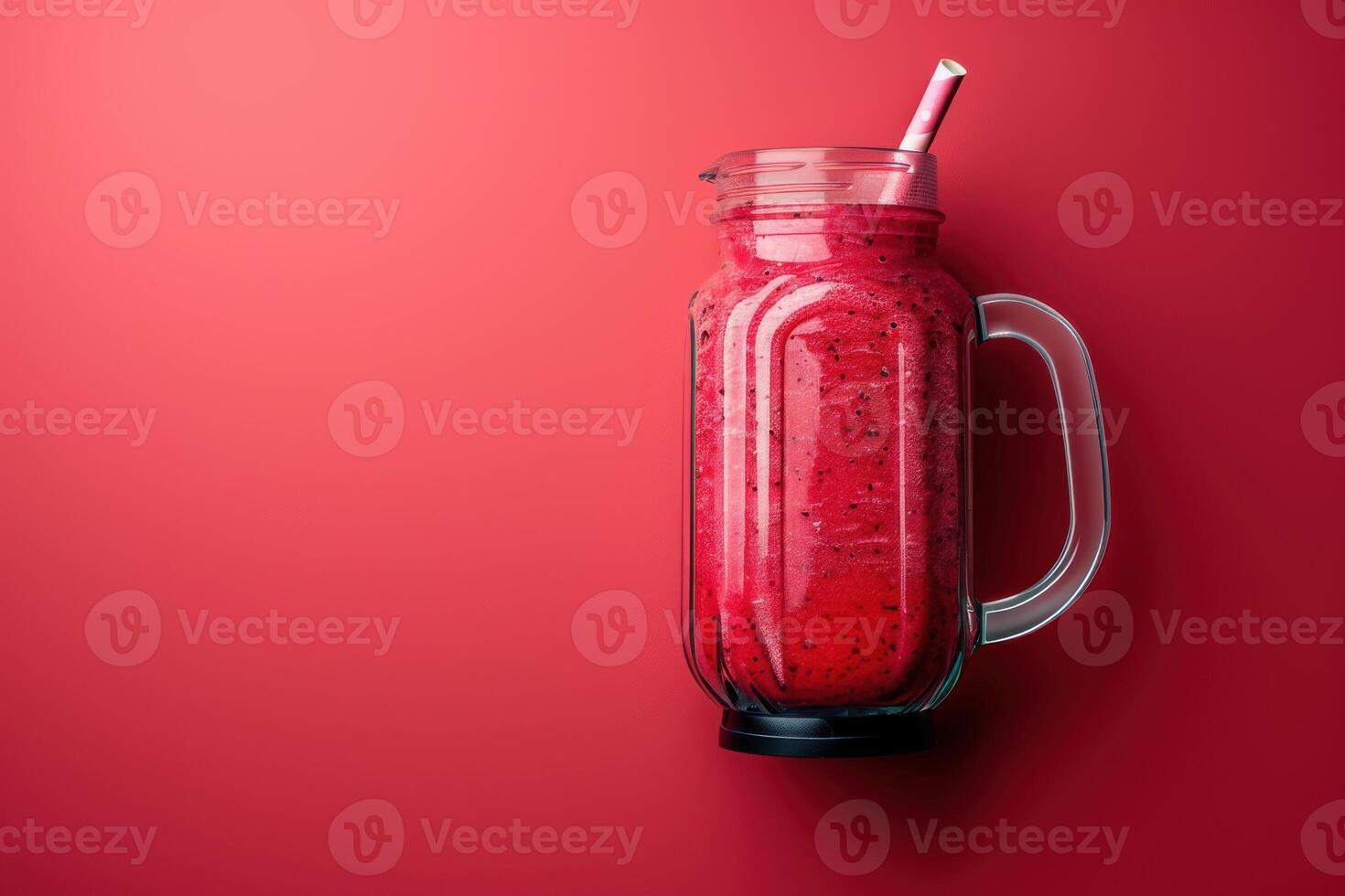 Vibrant raspberry smoothie in a glass jar against a bold red backdrop photo