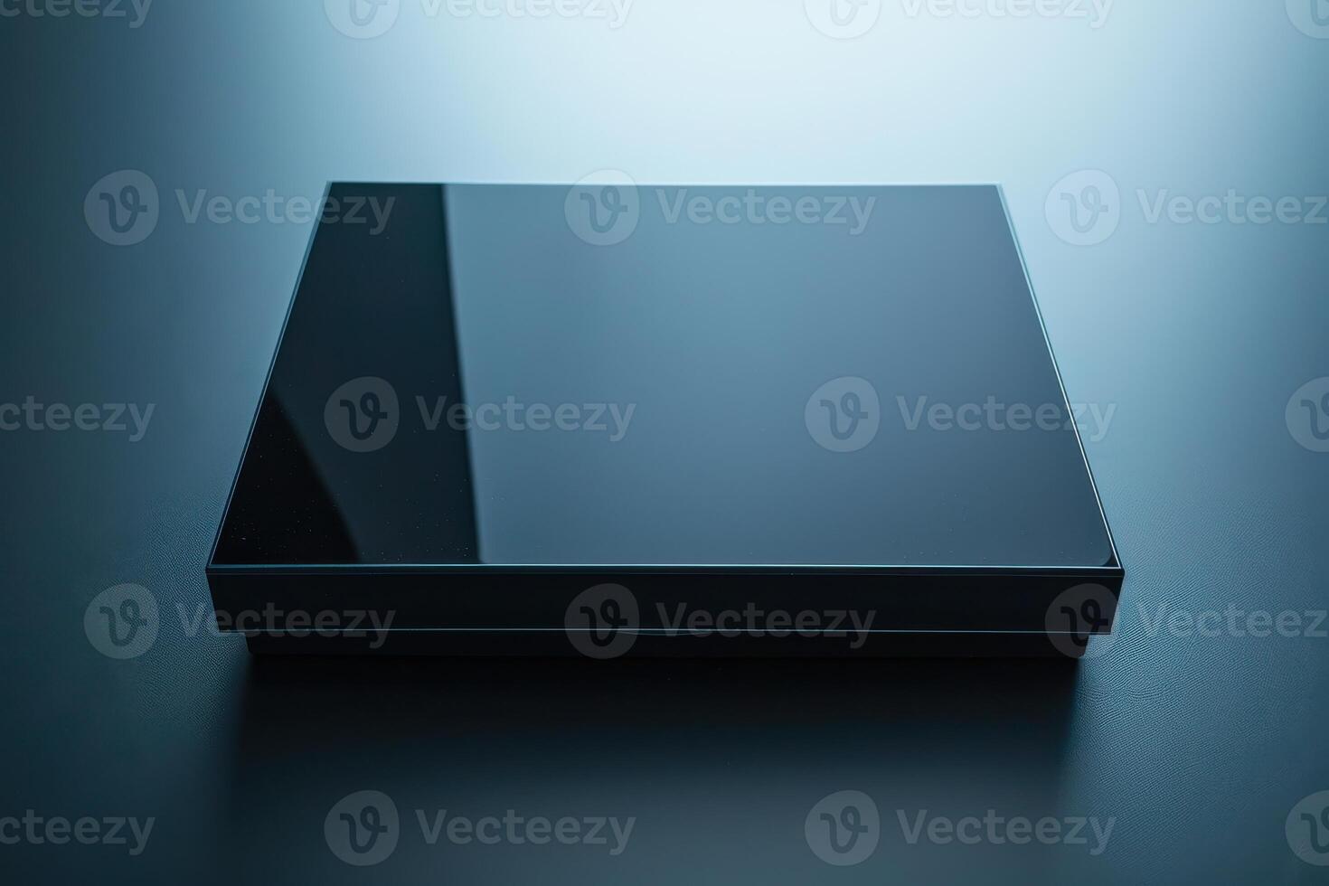 Glossy black square-shaped object resting on a textured surface illuminated by soft ambient light during twilight photo