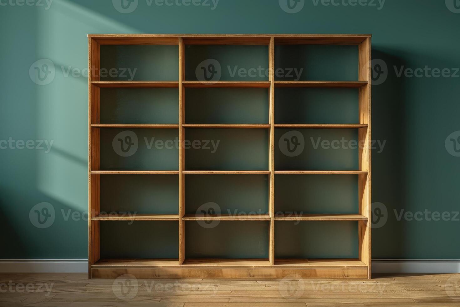 A wooden bookshelf casts long shadows in a sunlit room against a serene green wall photo