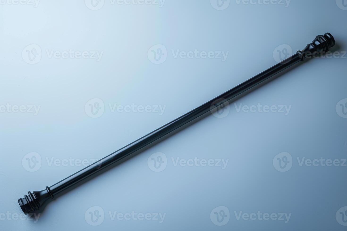 A sleek, elongated black wand resting on a smooth surface, capturing a minimalist aesthetic in soft lighting photo
