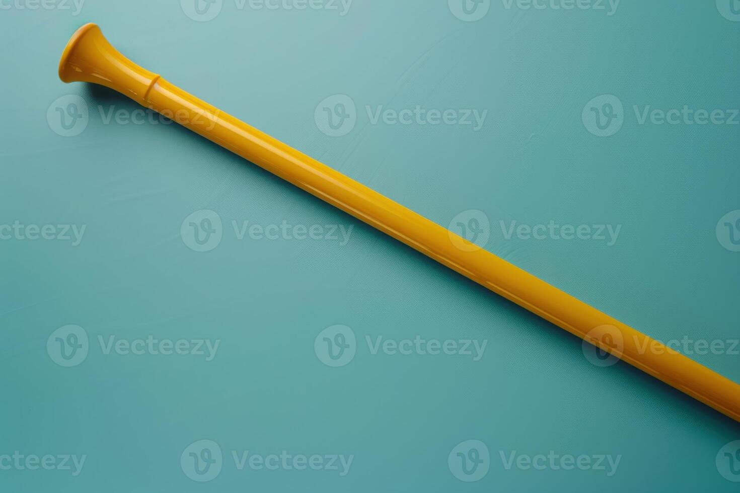 A vibrant yellow trumpet-shaped tool rests on a teal background, showcasing a playful contrast and simple elegance in design photo