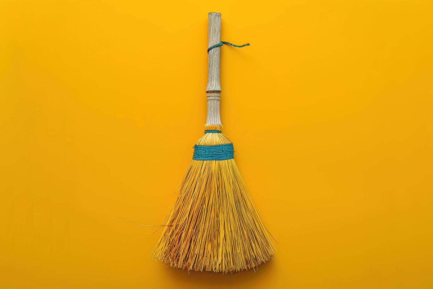 A bright yellow broom with a blue band stands against a vivid yellow backdrop, embodying the essence of cleanliness and simplicity photo