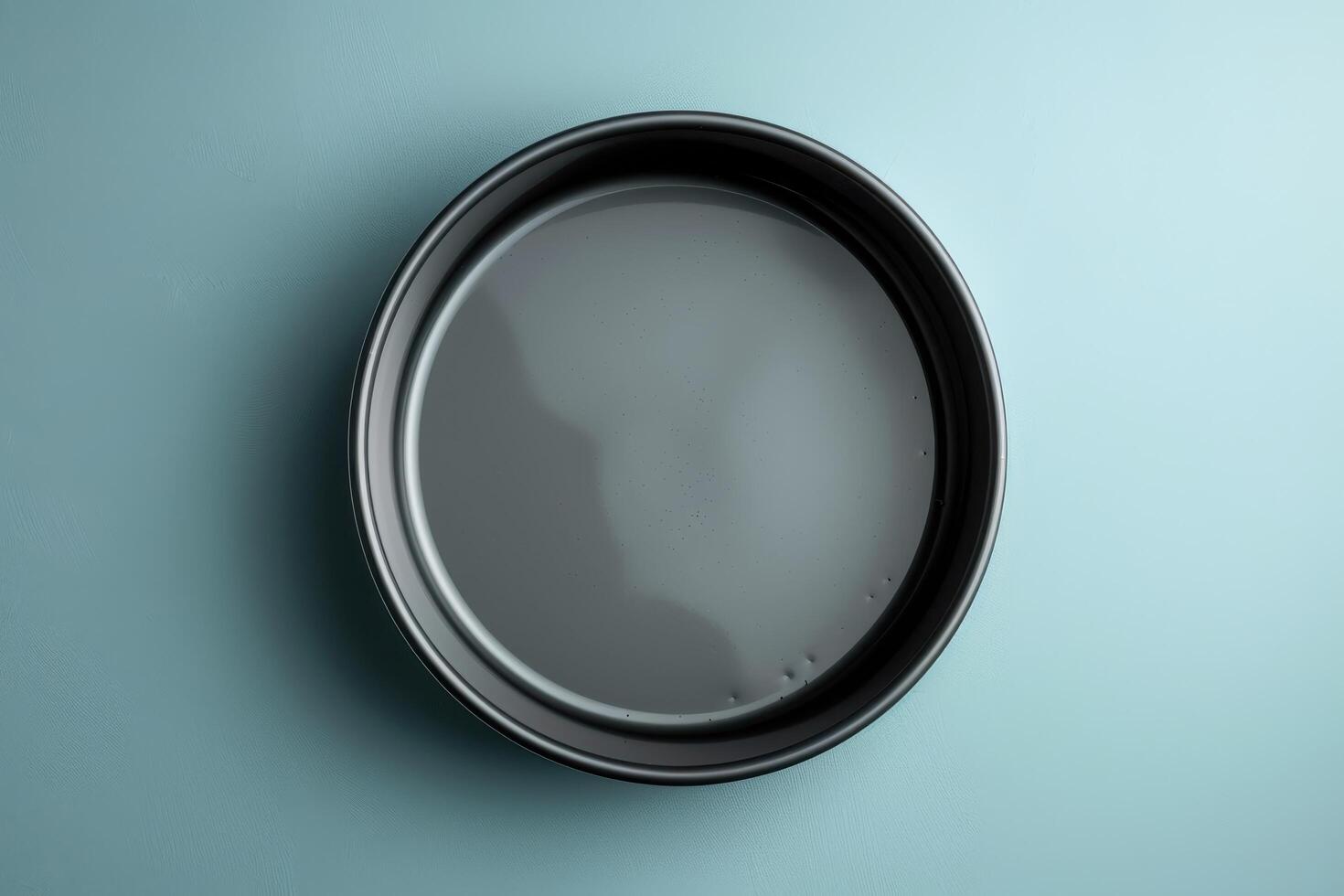 A sleek black plate resting on a calm blue surface, ready for a culinary masterpiece, captured in soft lighting photo
