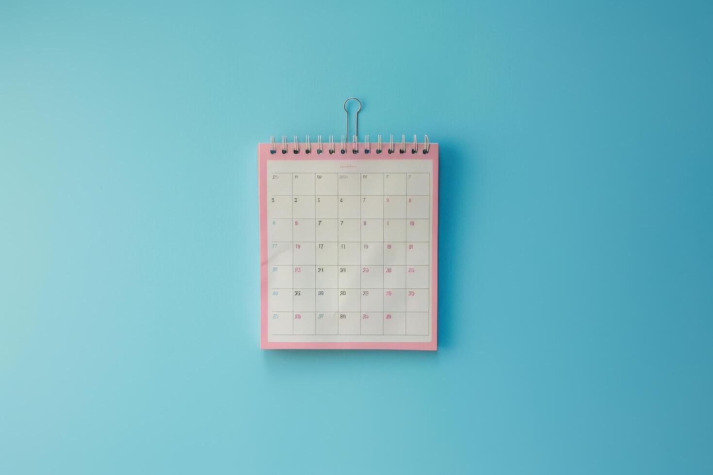 A colorful desk calendar hanging against a bright blue wall, marking important dates and events for the month ahead photo