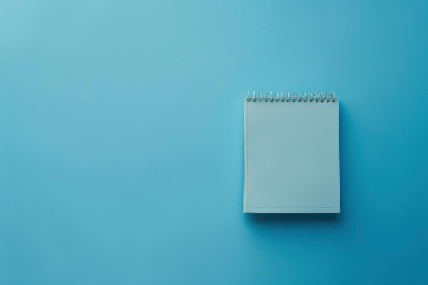 A blank notepad resting on a calming blue background, inviting creativity and ideas to flow freely photo