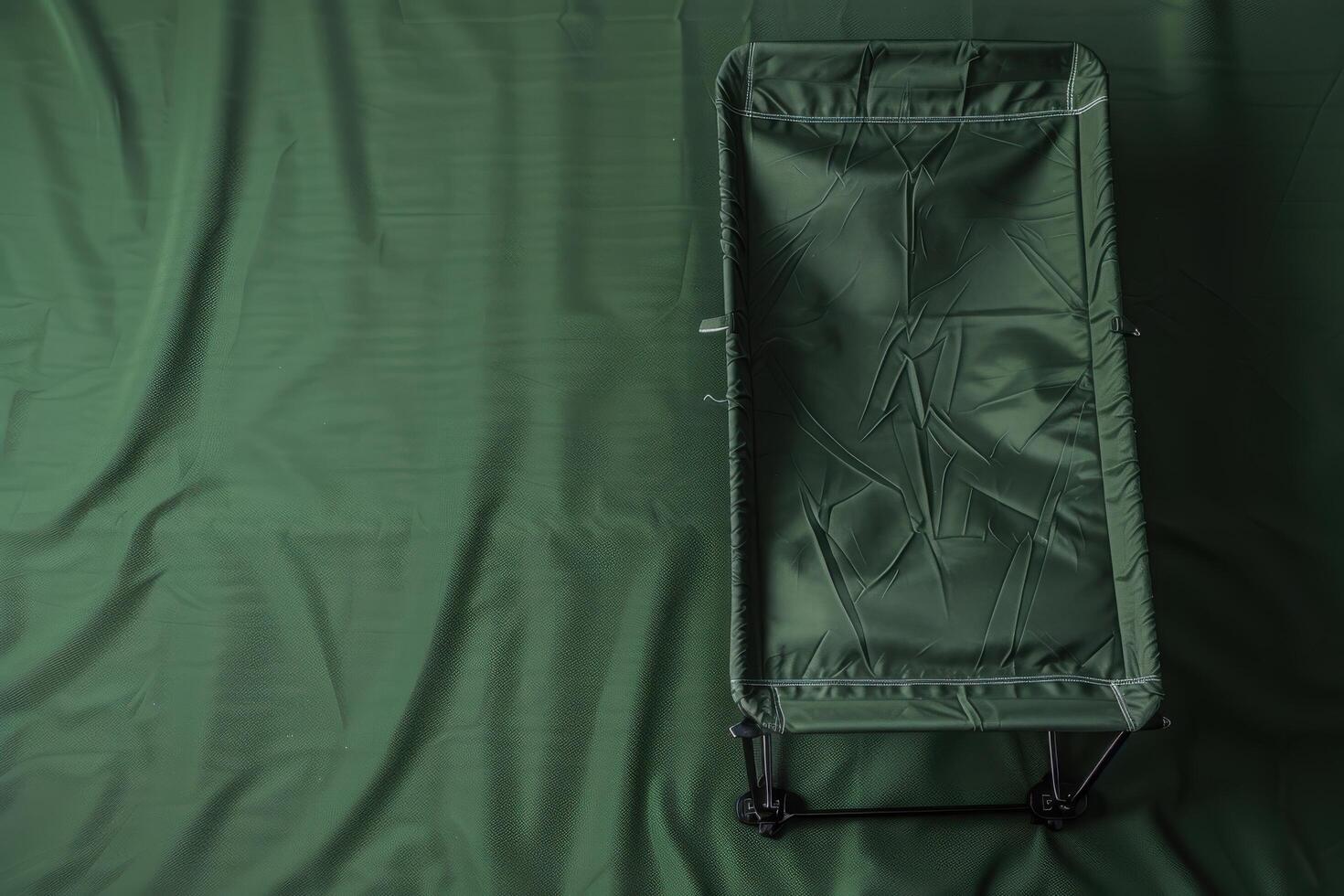 A solitary military cot resting on a deep green canvas during twilight, evoking a sense of peace and preparation for the night ahead photo