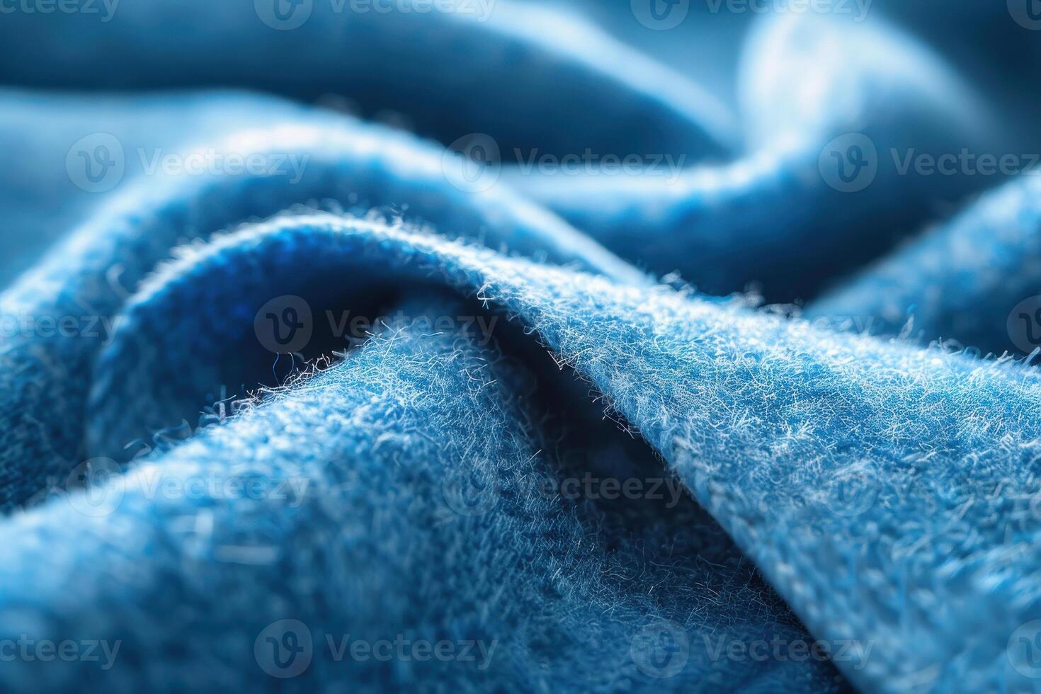 Close-up view of textured blue fabric showcasing fine fibers and intricate weave patterns in soft lighting photo