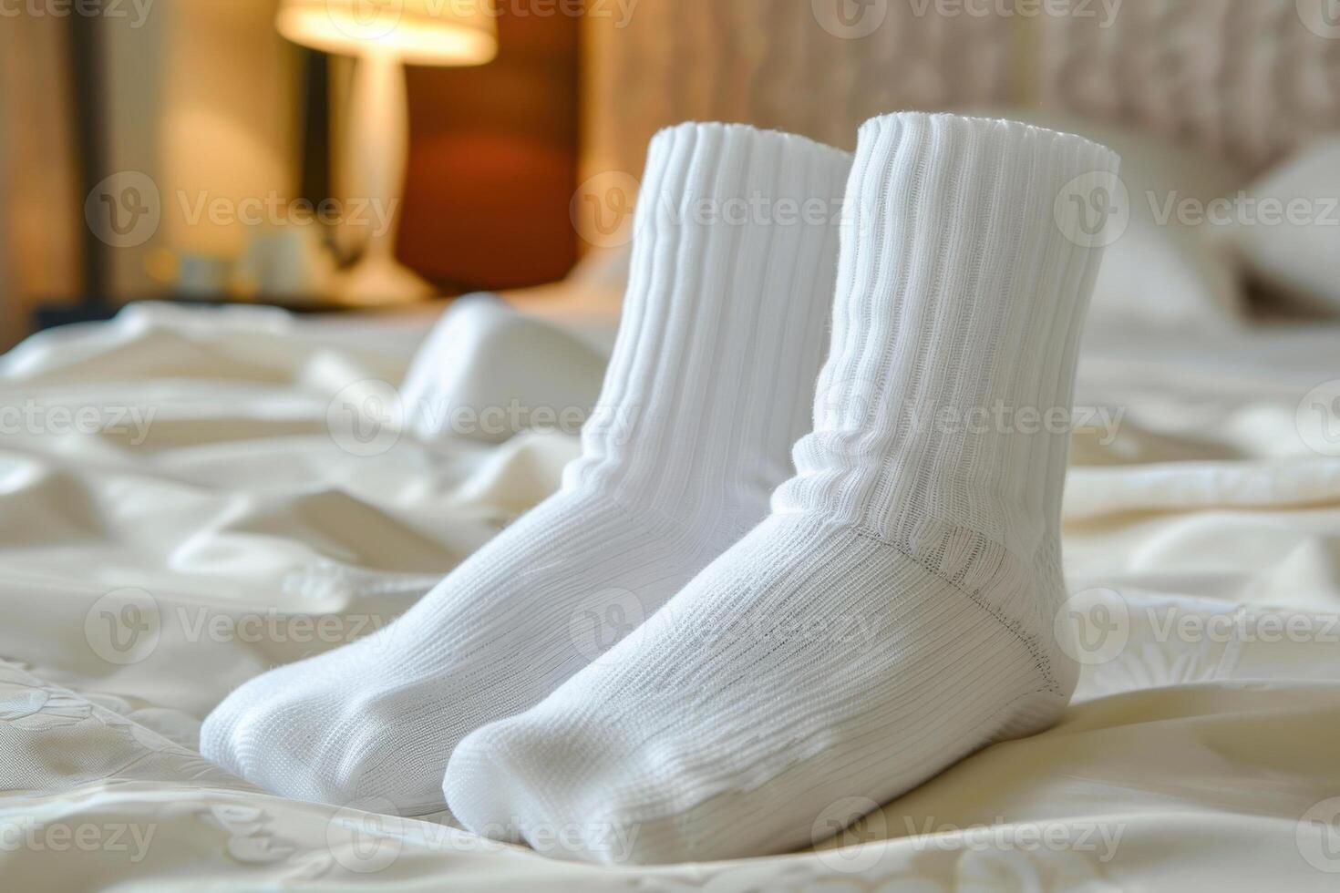 Two white socks neatly placed on a bed in a cozy hotel room during the morning photo