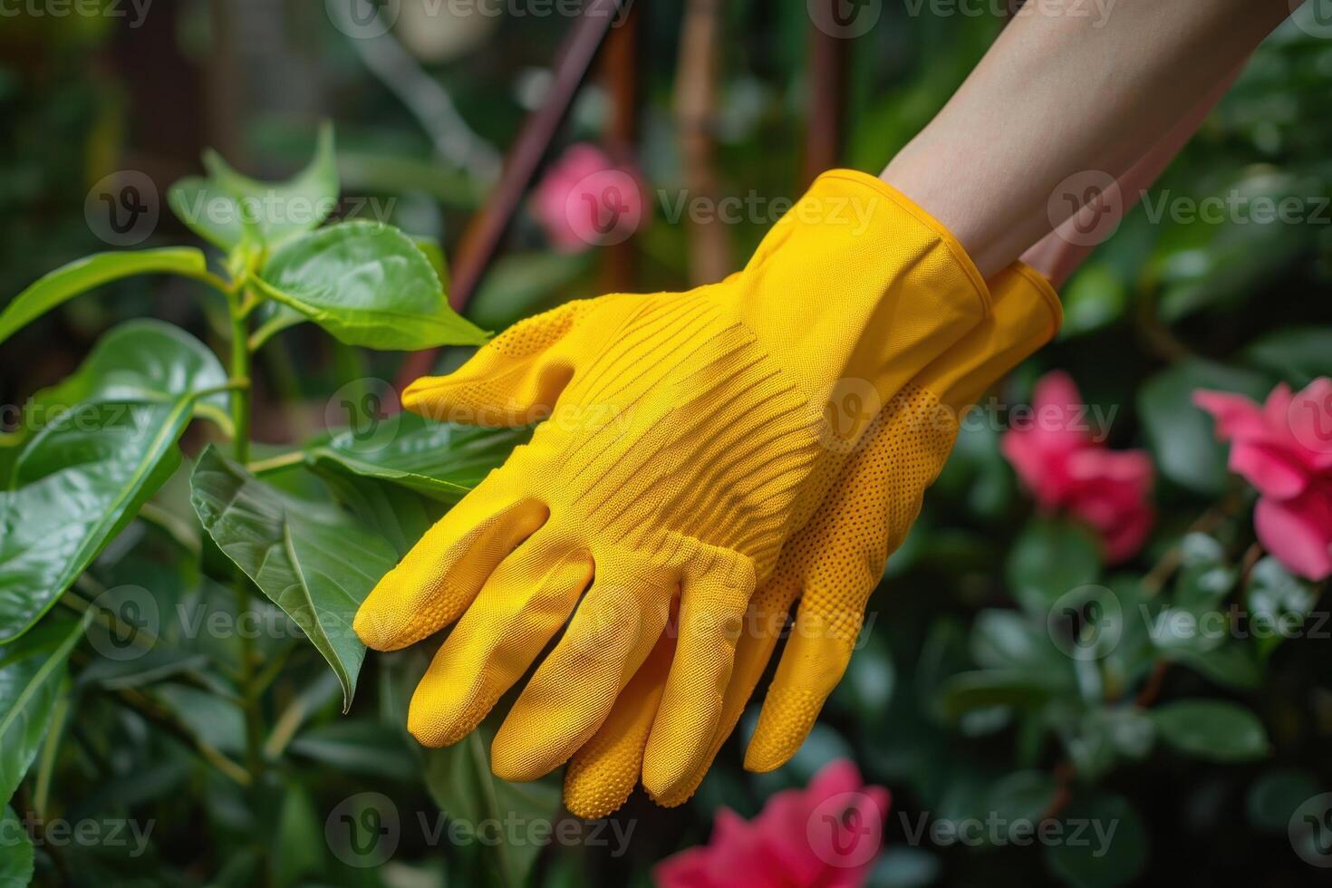 A person wearing yellow gardening gloves near vibrant flowers in a lush garden during daylight photo