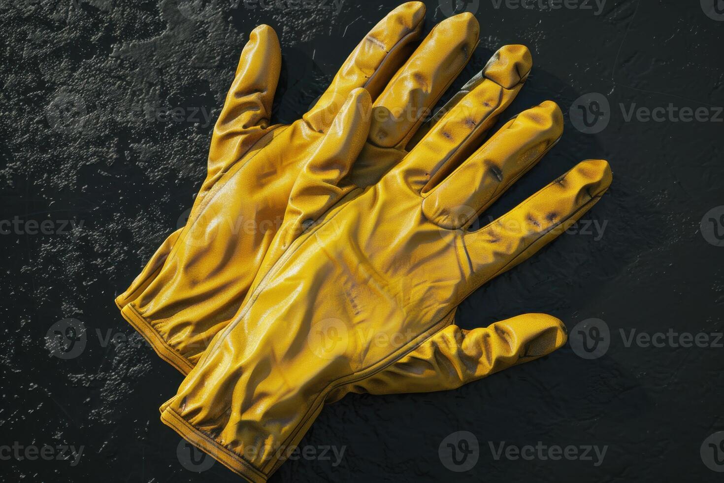 Yellow rubber gloves placed on a dark surface photo