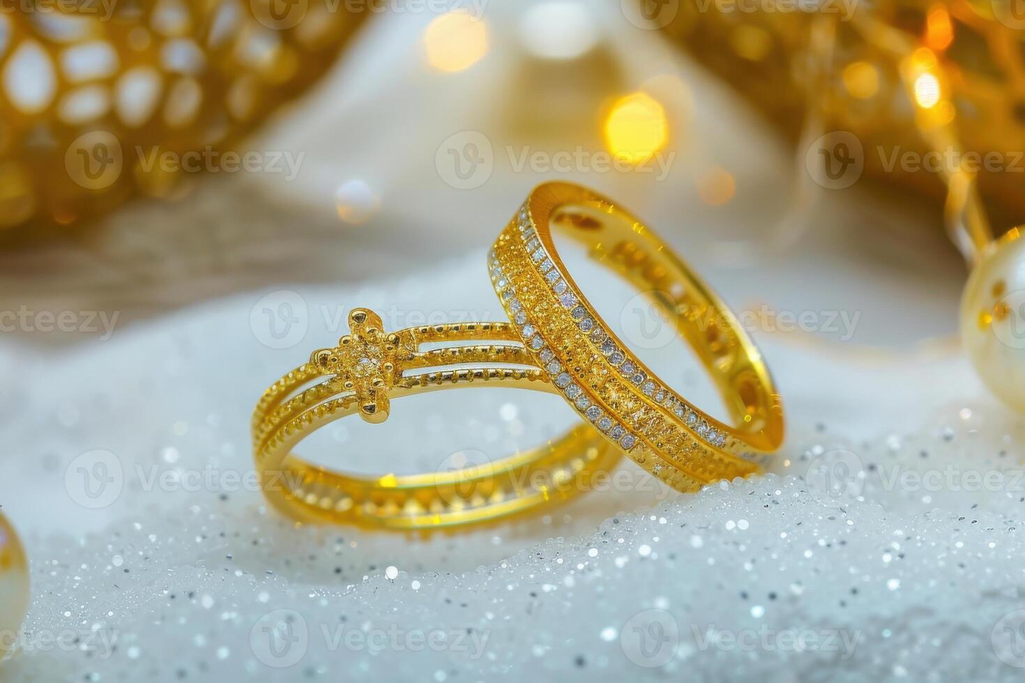Elegant gold and diamond rings resting on glittering snow with warm background lights photo