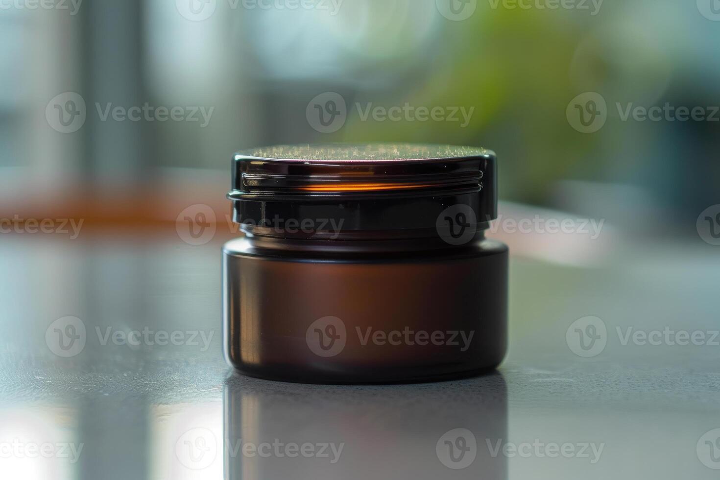 Dark glass jar on a reflective surface with blurred background in a well-lit environment photo