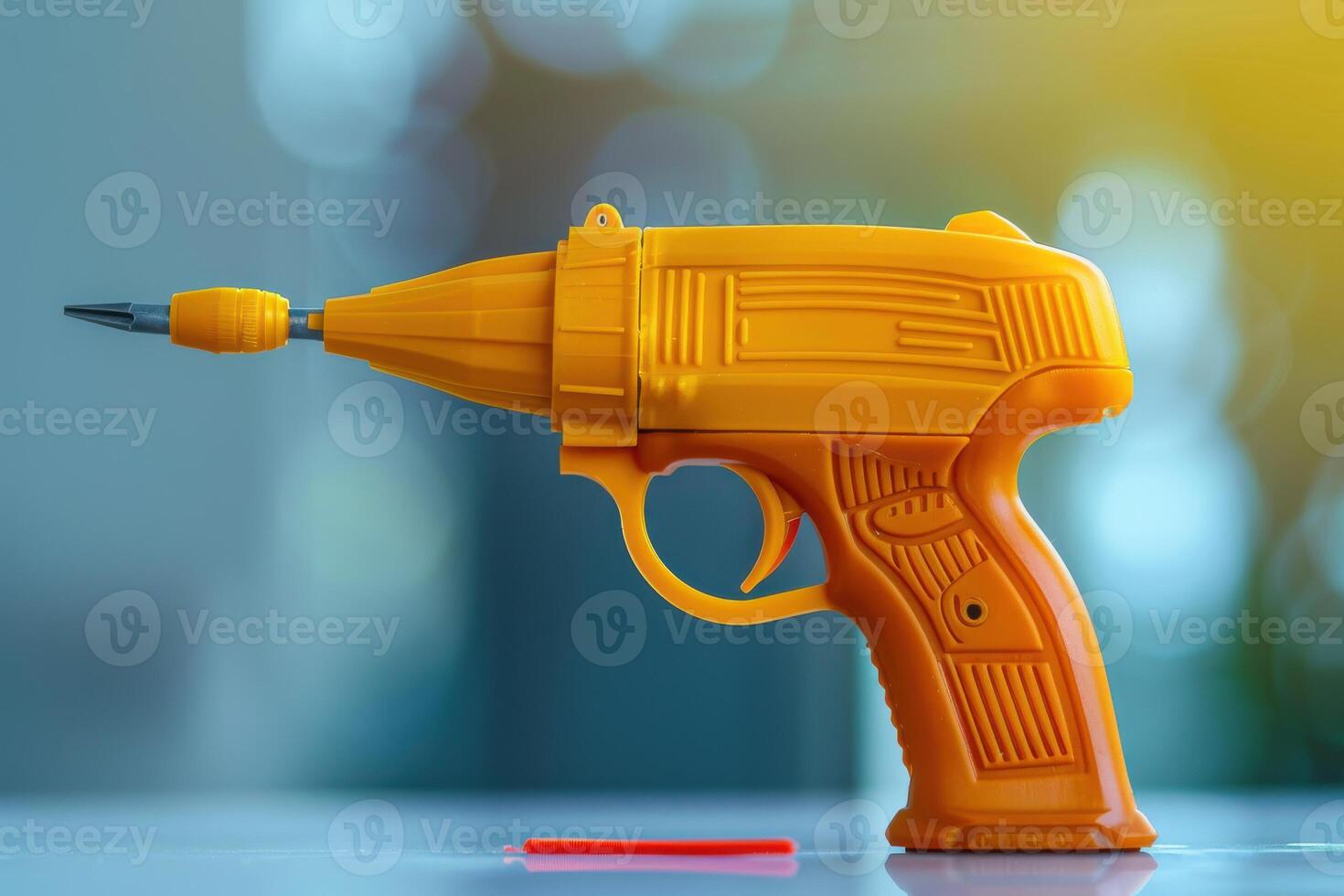 A bright orange plastic toy gun designed for kids, resting on a table with a red cap nearby during daylight photo