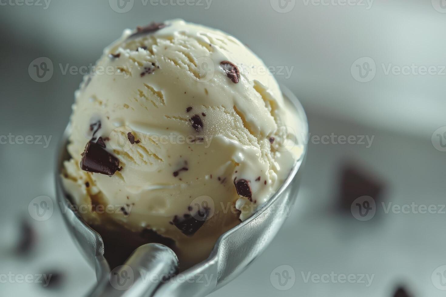 Creamy vanilla ice cream scoop with chocolate chunks on a silver scoop photo