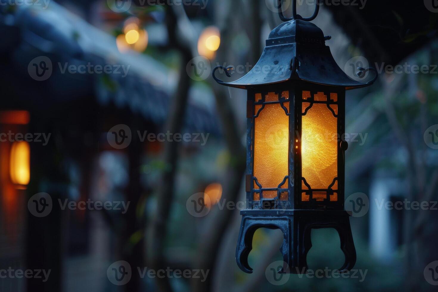 Lantern hanging in a serene garden at dusk with warm light illuminating the surroundings photo