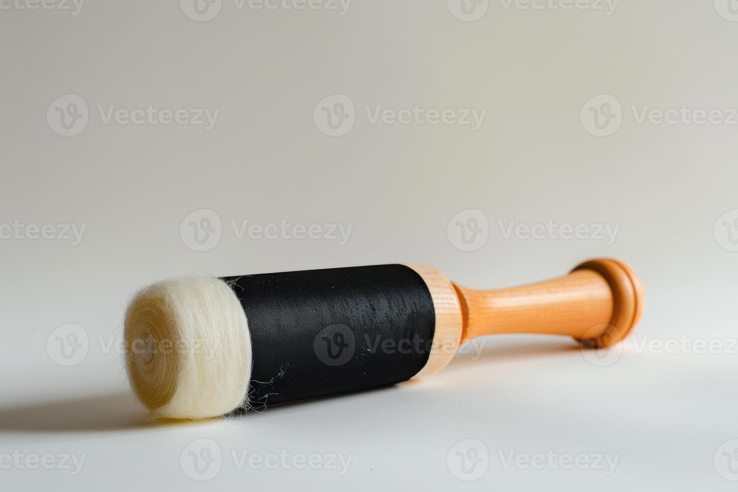 Wooden roller with black fabric and white felt for crafting on a neutral background photo