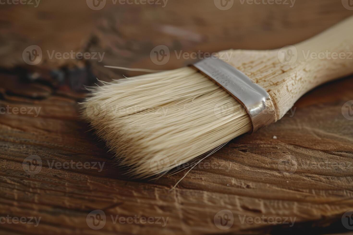 Close-up of a paintbrush resting on a wooden surface, showcasing its bristles and handle in natural lighting photo