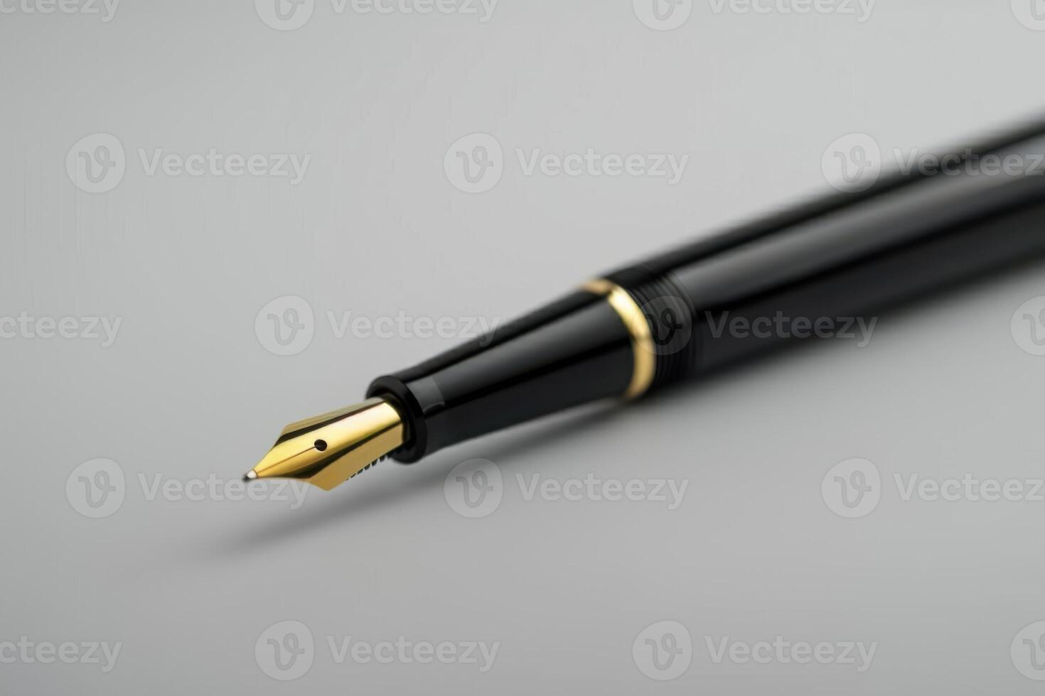 Close-up of a sleek black fountain pen with a golden nib on a gray background photo