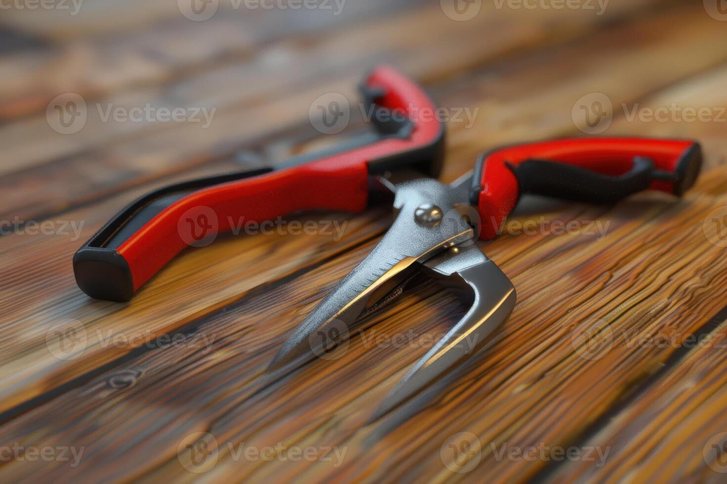 Sharp gardening shears with red handles resting on wooden table photo