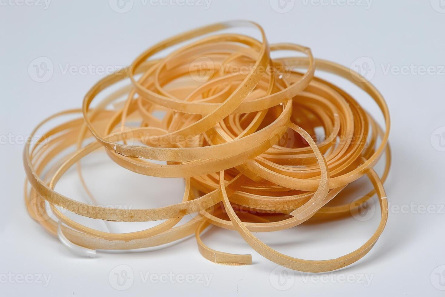 Rolled rubber bands scattered on a white surface, showcasing their flexible texture and varying sizes photo