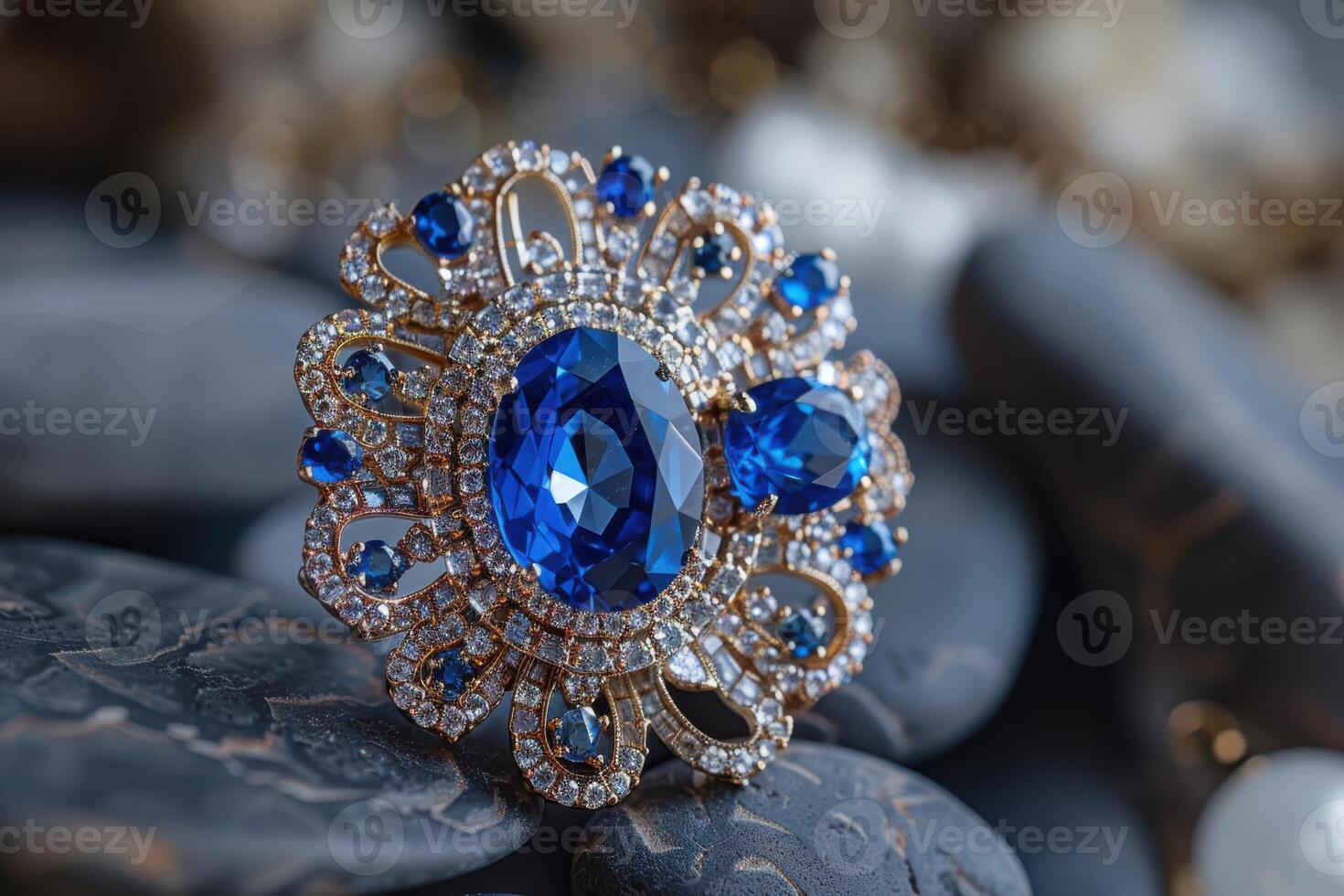 Elegant blue gemstone brooch displayed on smooth dark stones in a soft light setting photo
