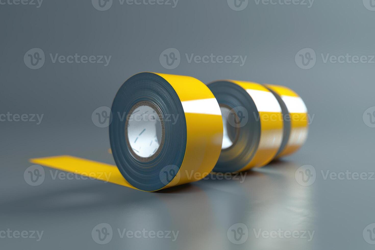Yellow caution tape rolls on a gray surface with reflective striping during daylight photo