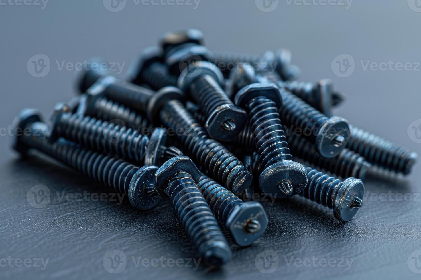 Close-up view of a pile of metal screws on a dark surface photo