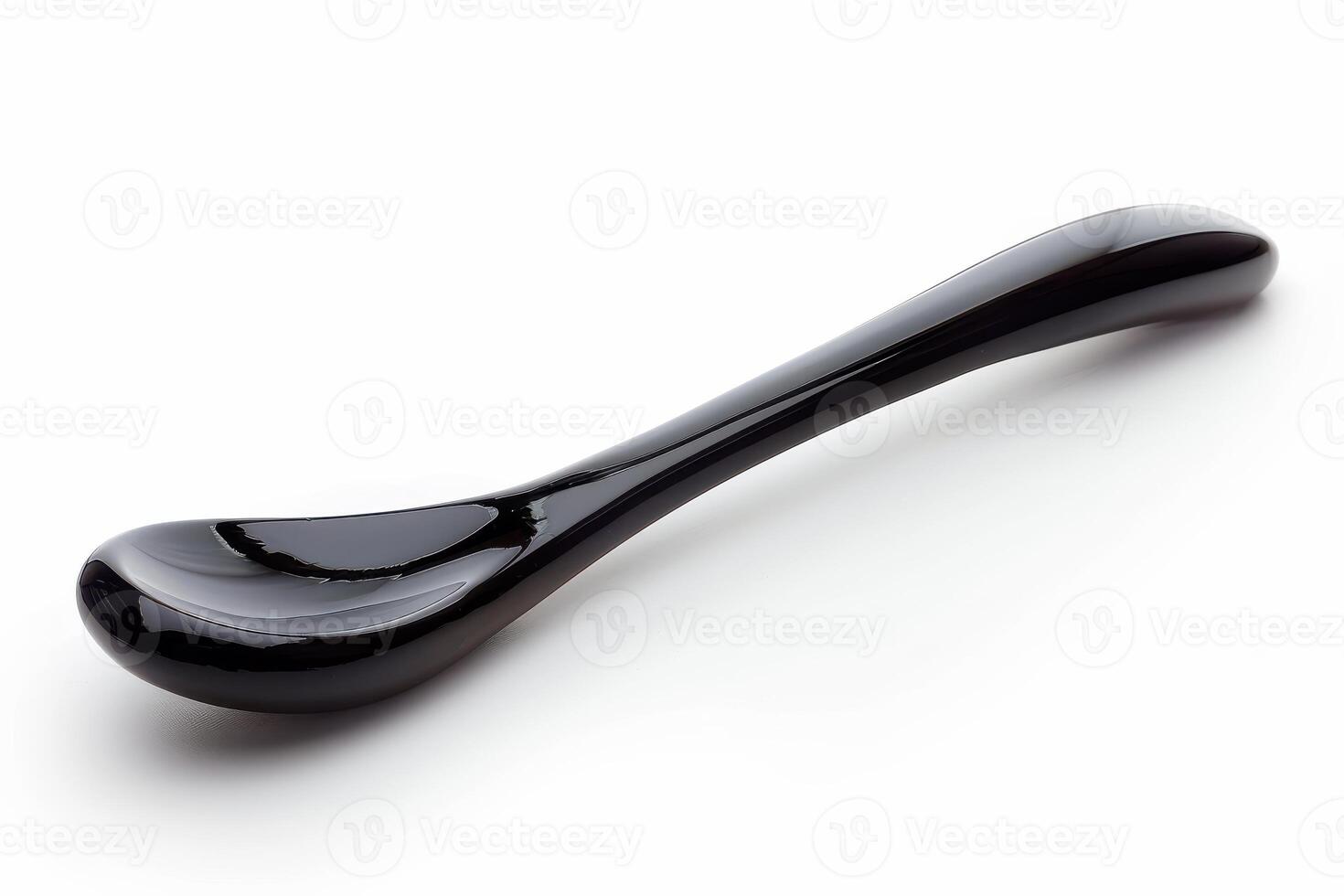 Elegant black ceramic spoon resting on a smooth surface, showcasing its sleek design and unique shape in bright light photo